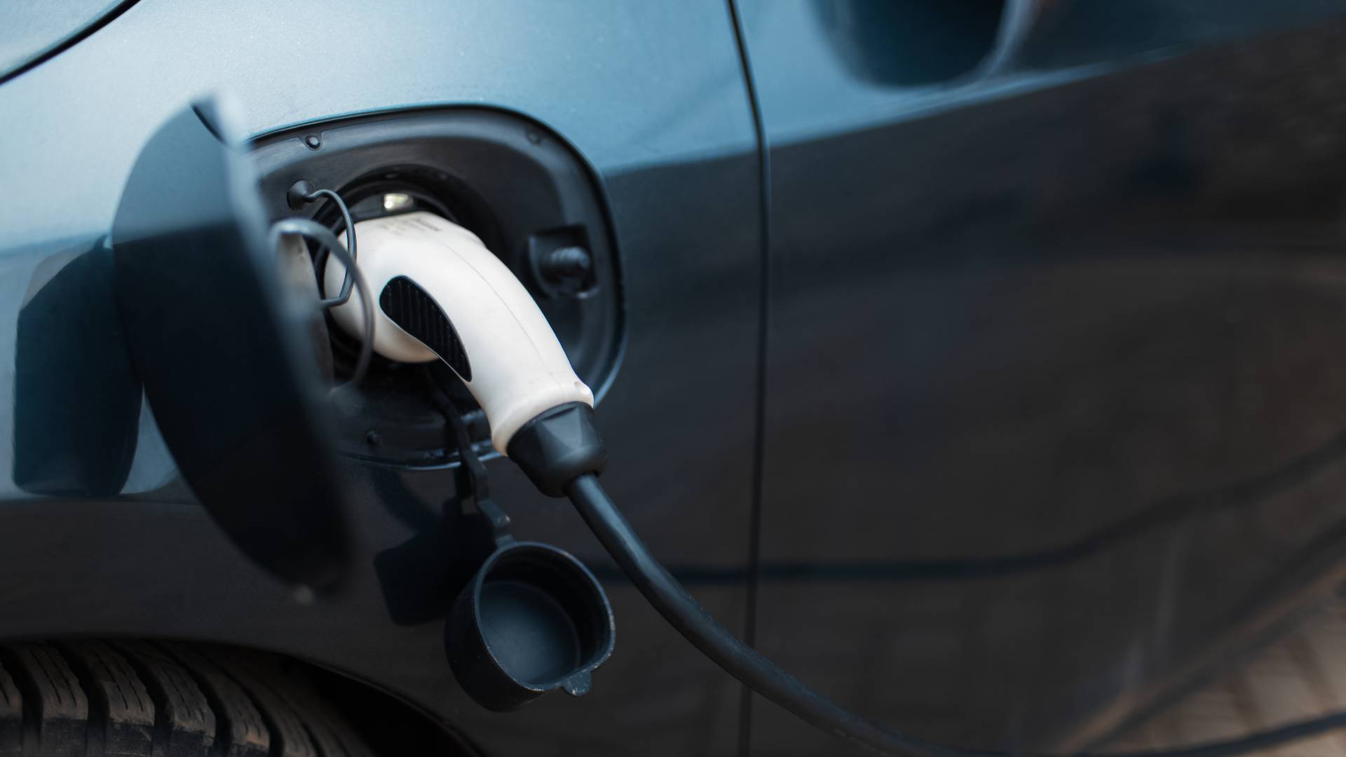 AdobeStock_481571950 Electric vehicle charging cable plugged into EV charging port on car