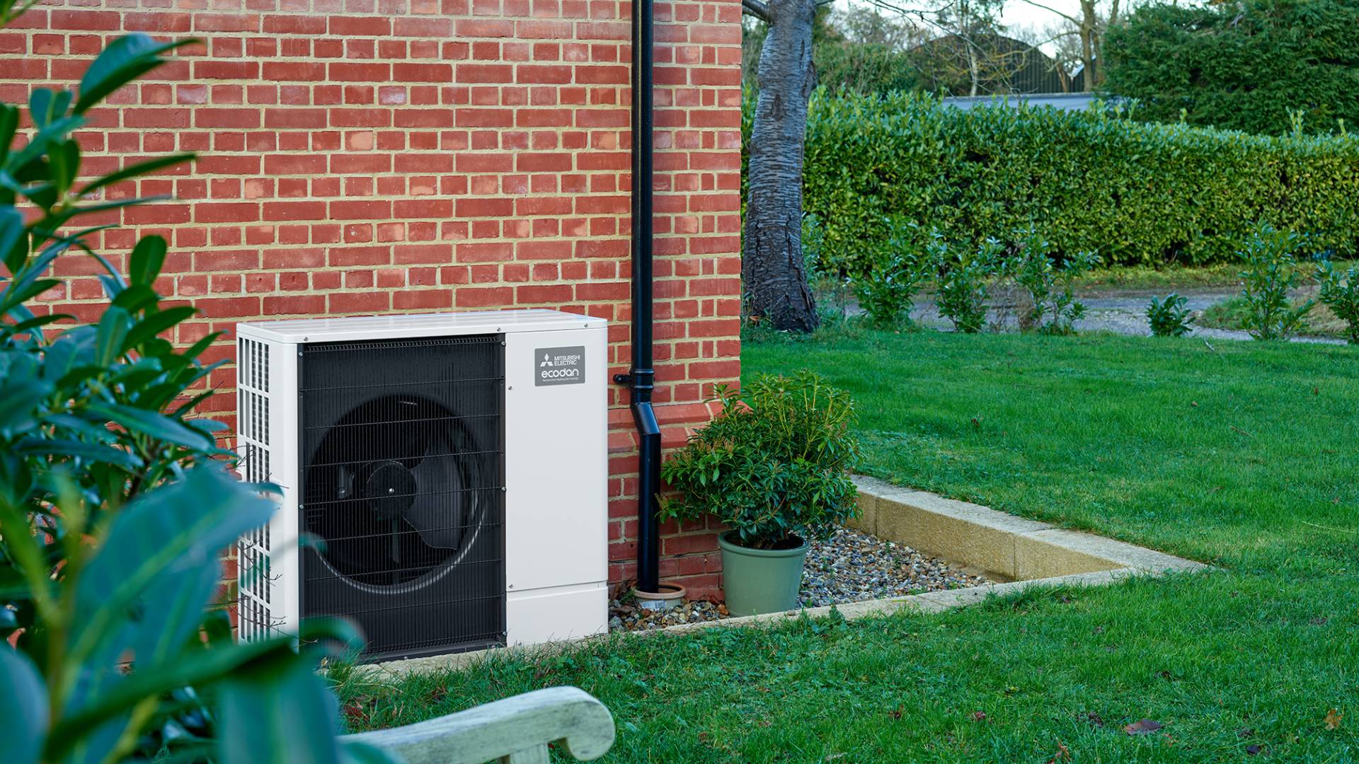 Ecodan-Heat-Pump-Garden-Back-Drop (1) Mitsubishi Electric Ecodan air source heat pump installed externally beside brick house with garden lawn