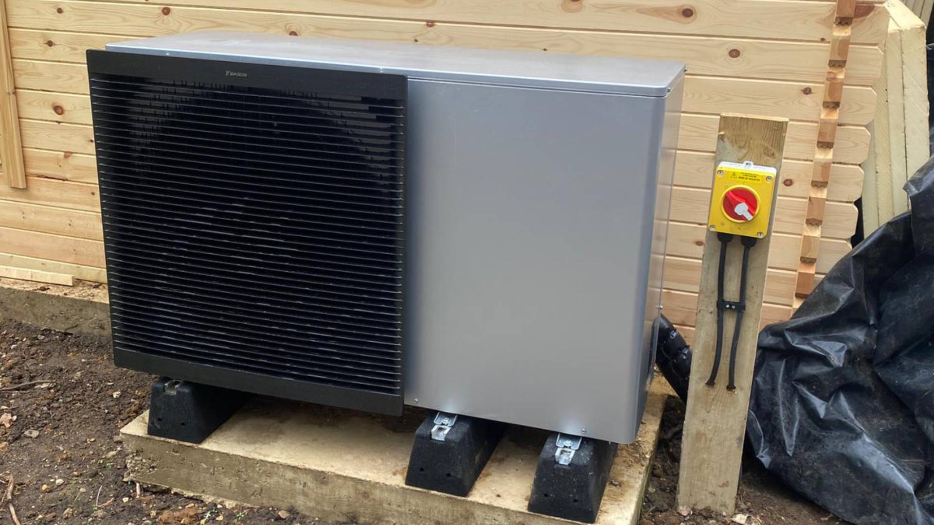 PHOTO-2024-07-23-15-39-45 (1) Daikin air source heat pump unit installed externally on concrete base with isolation switch