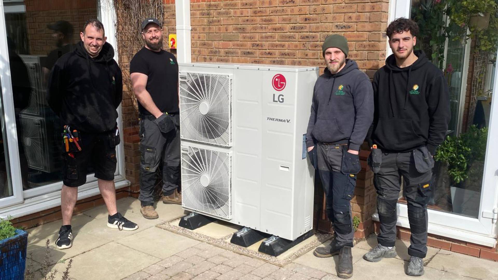 RT Solar installation team standing beside LG Therma V air source heat pump outside residential property