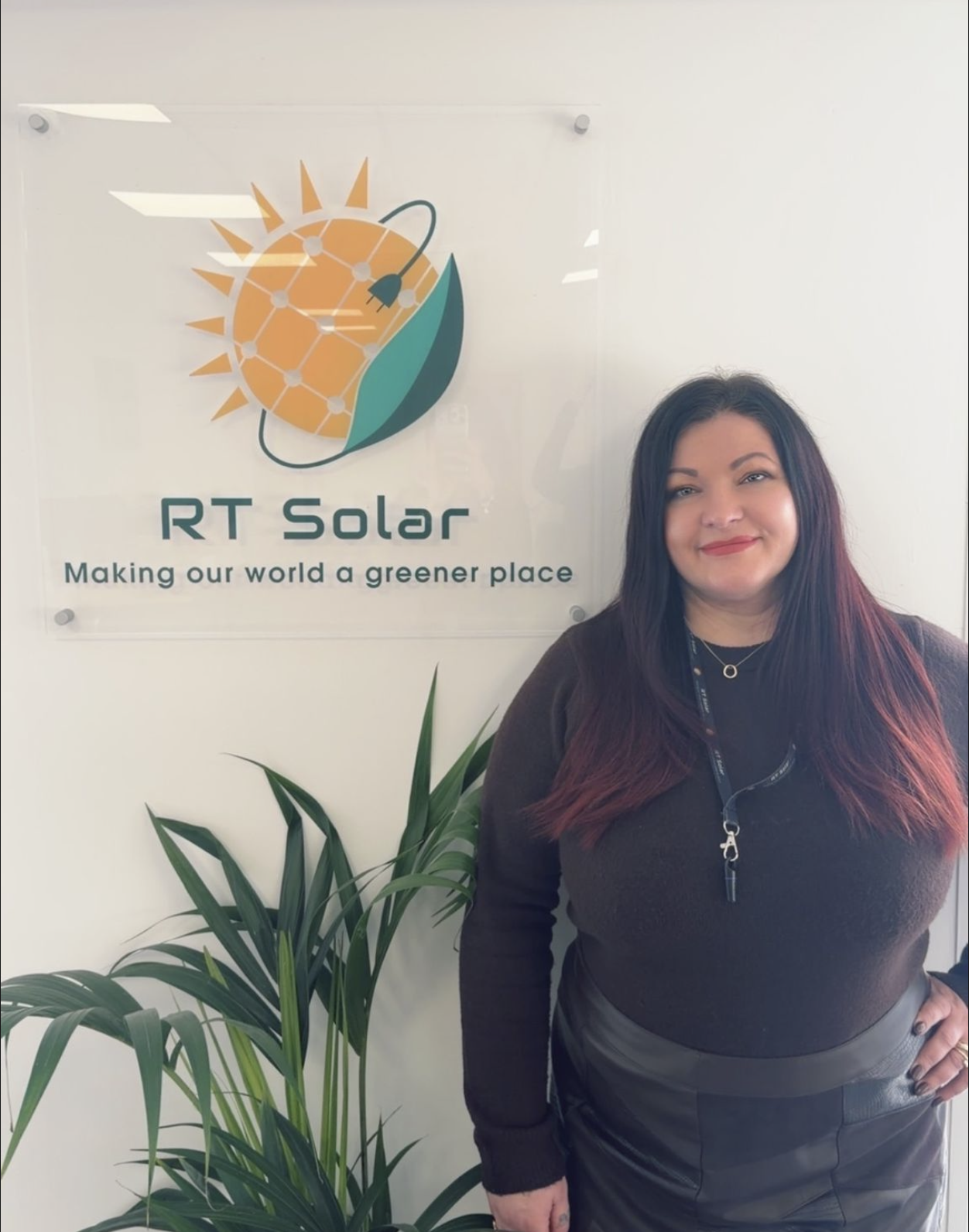 Teddy – RT Solar RT Solar office team member standing beside company renewable energy logo sign