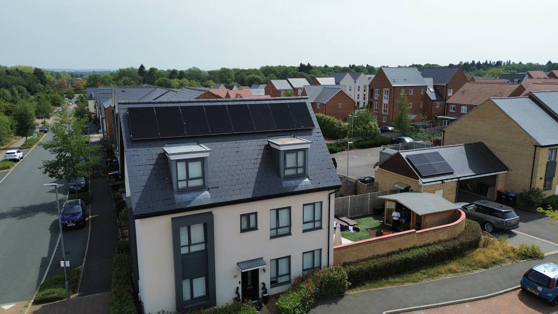 Modern home with black roof solar panels in residential estate.
